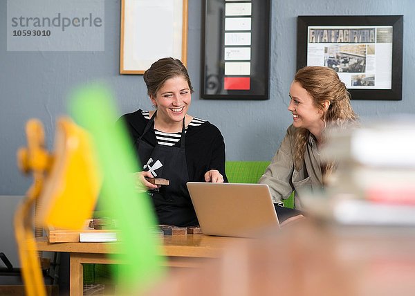 Druckerin und Designerin mit Laptop im Werkstattbüro