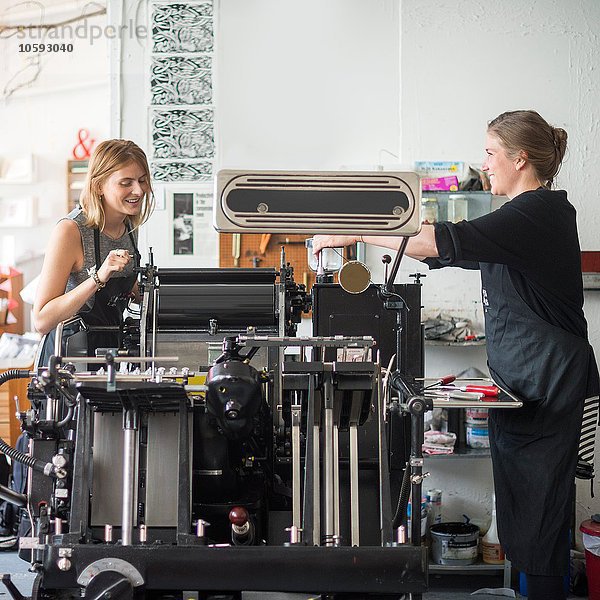 Zwei Frauen arbeiten mit traditioneller Buchdruckmaschine in der Werkstatt