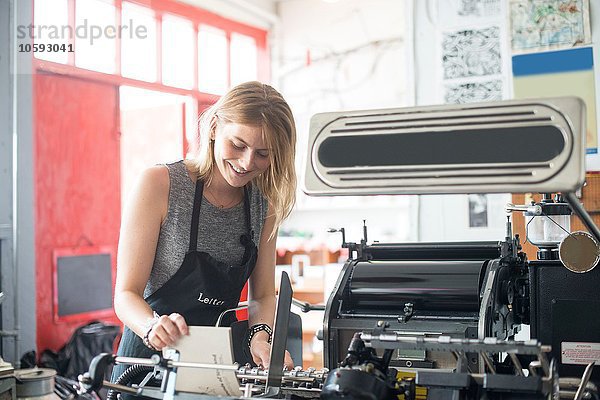 Junge Frau arbeitet mit traditioneller Buchdruckmaschine in der Werkstatt