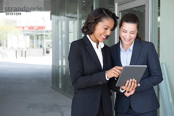 Zwei Geschäftsfrauen  die sich das digitale Tablett ansehen  im Freien