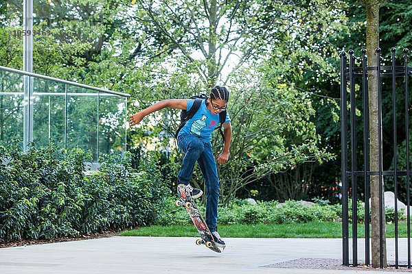 Junge macht Skateboard-Trick auf städtischem Bürgersteig