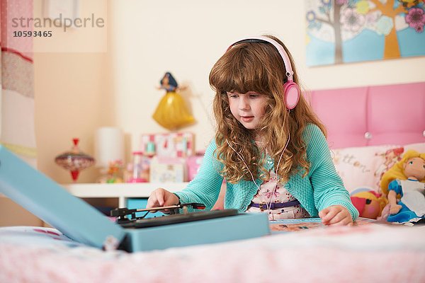 Mädchen im Schlafzimmer trägt Kopfhörer und spielt Vinyl-Schallplatten.