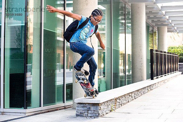 Junge macht Skateboard-Tricksprung an der Stadtmauer