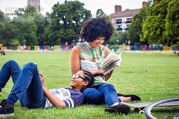 Junge und Mutter entspannen und lesen Buch im Park