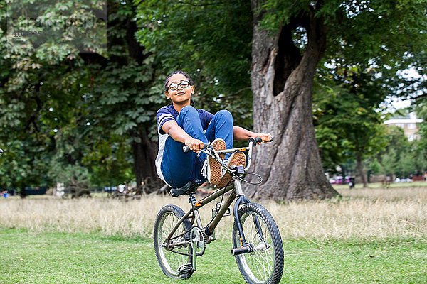 Junge fährt BMX Fahrrad mit Füßen oben im Park