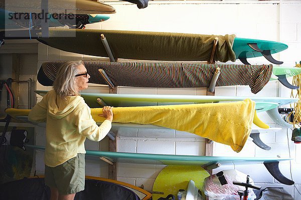 Seniorin nimmt Surfbrett aus dem Regal