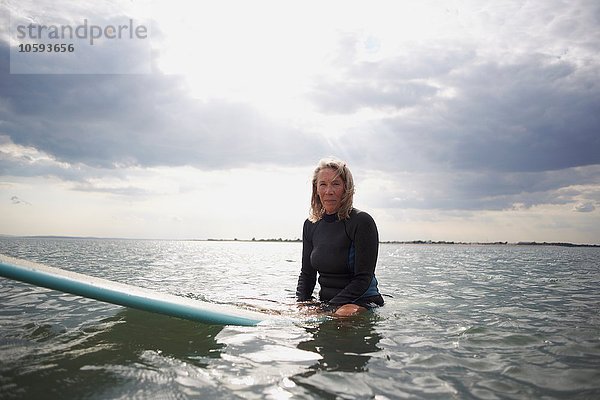 Porträt einer älteren Frau auf dem Surfbrett im Meer