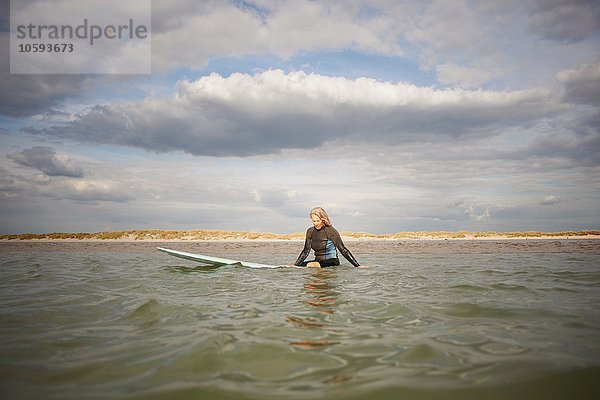 Seniorin auf dem Surfbrett im Meer sitzend