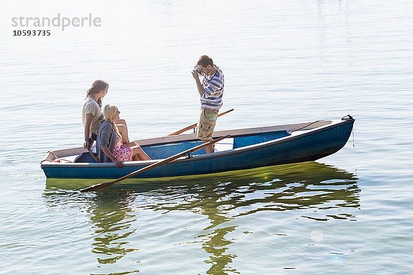 Seitenansicht eines jungen Mannes im Boot auf dem See  der Frauen fotografiert.