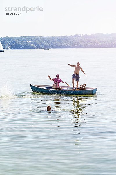 Freunde springen vom Boot und schwimmen im See  Schondorf  Ammersee  Bayern  Deutschland