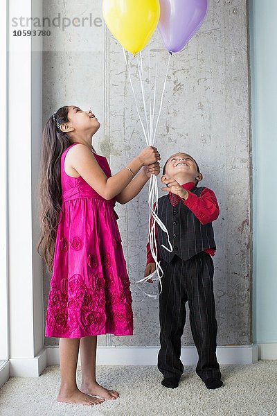 Junges Mädchen und Junge  mit Luftballons.