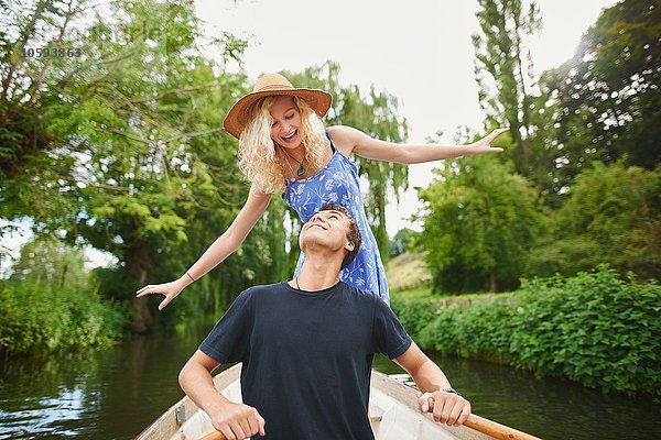 Junge Frau mit Freund im Ruderboot auf dem Fluss stehend