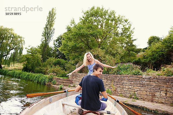 Rückansicht der jungen Frau mit ihrem Freund im Ruderboot auf dem Fluss