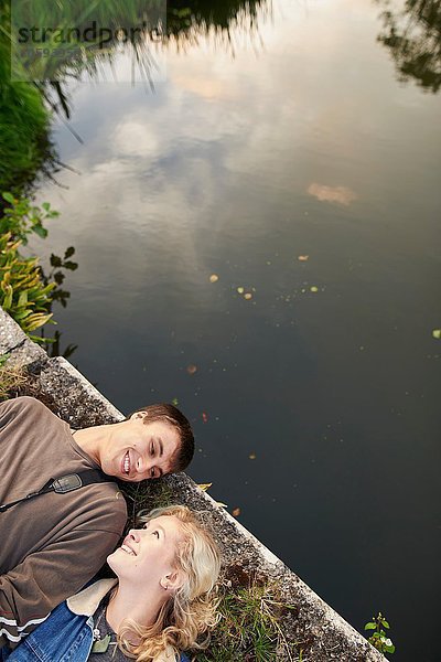 Draufsicht auf ein junges Paar  das auf einer Flussbrücke liegt.