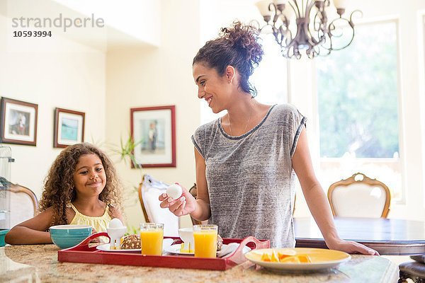 Mutter und Tochter zu Hause beim Zubereiten des Frühstückstabletts lächelnd
