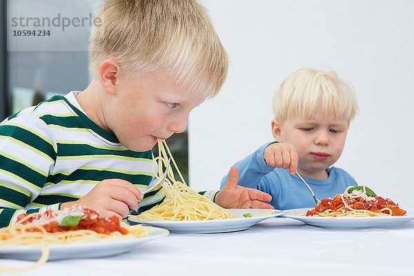 Junge und Kleinkind Bruder essen Spaghetti auf der Terrasse