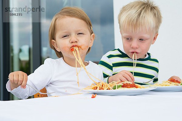 Junge und Kleinkind essen Spaghetti auf der Terrasse