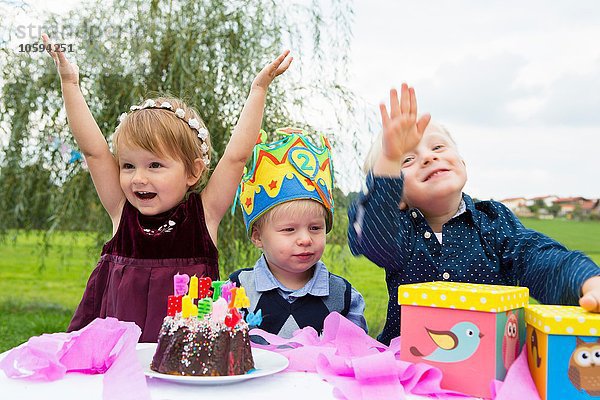 Weibliches Kleinkind und zwei junge Brüder bei der Geburtstagsfeier im Garten