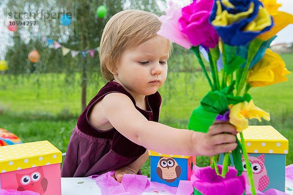 Weibliches Kleinkind mit Papierblumen bei der Geburtstagsfeier im Garten