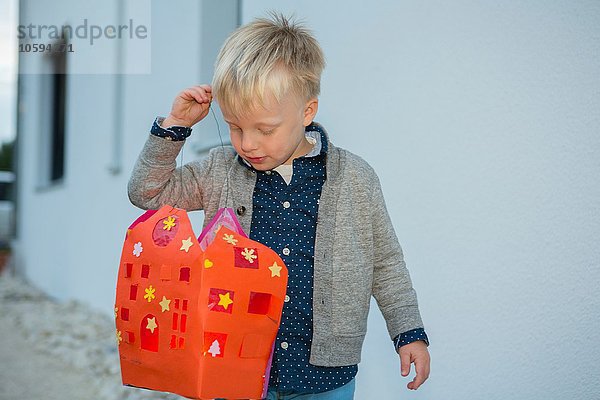 Junge mit selbstgemachter Weihnachtslaterne auf der Terrasse