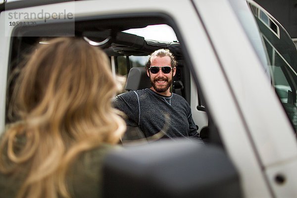 Über die Schulteransicht einer jungen Frau  die mit ihrem Freund im Jeep chattet.