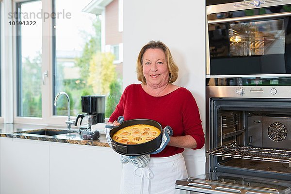 Porträt der Seniorin mit Kuchen in der Küche