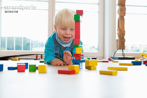 Männliches Kleinkind beim Spielen mit Bausteinen auf dem Wohnzimmerboden