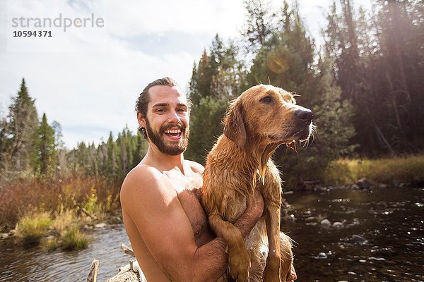 Porträt eines jungen Mannes mit seinem nassen Hund am Fluss  Lake Tahoe  Nevada  USA