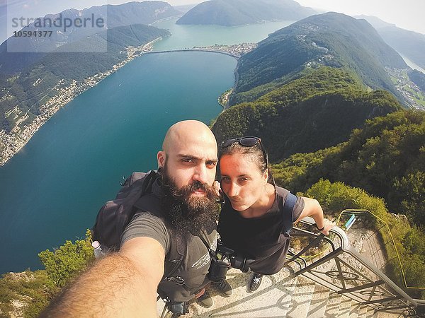 Hochwinkelaufnahme des mittleren erwachsenen Paares mit Selfie über dem Luganer See  Schweiz