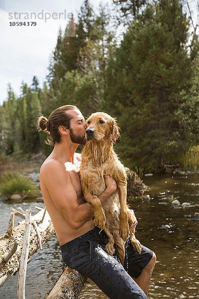 Junger Mann küsst seinen nassen Hund am Fluss  Lake Tahoe  Nevada  USA