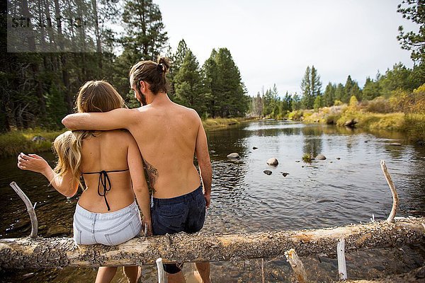 Rückansicht des jungen Paares auf einem umgestürzten Baum im Fluss  Lake Tahoe  Nevada  USA