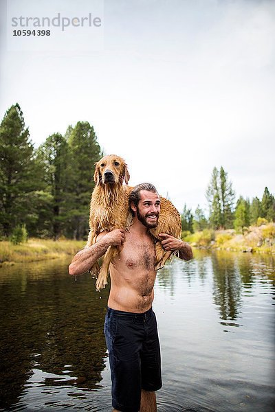 Junger Mann mit nassem Hund über den Schultern im Fluss  Lake Tahoe  Nevada  USA