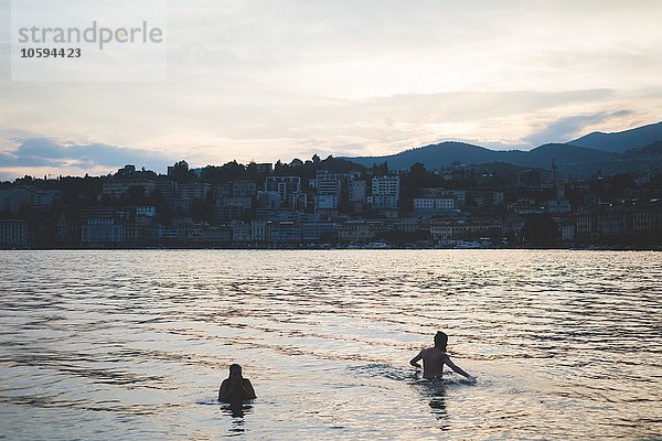 Zwei Scherenschnitt-Touristen schwimmen im Luganersee  Schweiz