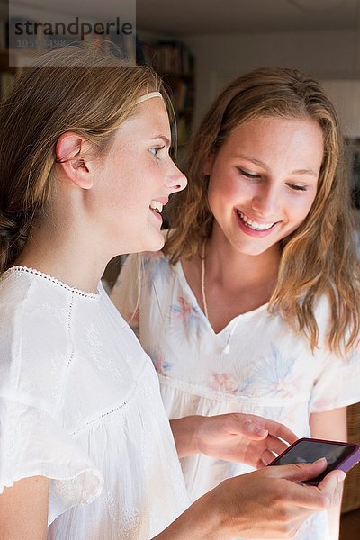 Zwei Teenager-Mädchen beim Lesen von Smartphone-Texten