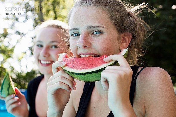 Zwei Teenagermädchen beim Essen von Wassermelonenscheiben im Garten