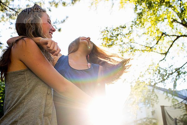 Zwei Teenager-Mädchen tanzen im sonnendurchfluteten Park