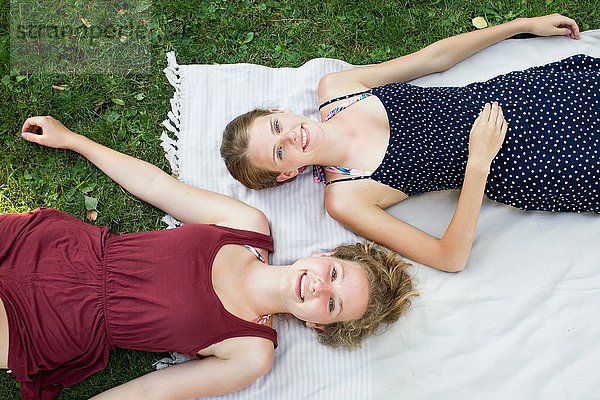 Overhead-Porträt zweier Teenager-Mädchen auf Picknickdecke im Park