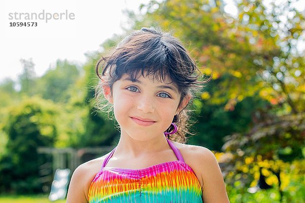 Porträt eines Mädchens in farbenfrohem Neckholder-Top mit lächelndem Blick auf die Kamera