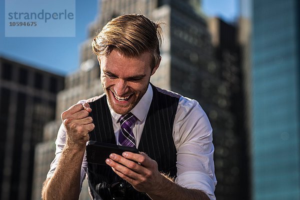 Junger Geschäftsmann vor der Bürofaust am Smartphone  New York  USA