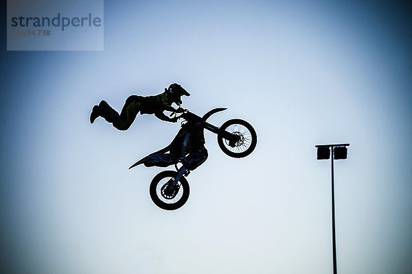 Mann  der extreme Stunts mit dem Motorrad in der Luft durchführt