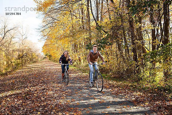 Teenager Junge und erwachsene Schwester radeln entlang der Herbstwaldstraße