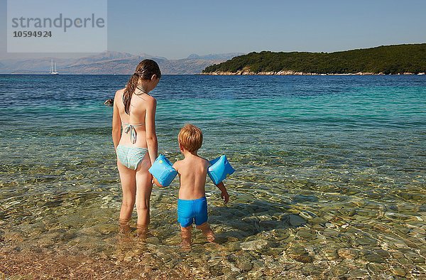 Rückansicht von Mädchen und Jungen mit blauen Armbinden beim Paddeln im Meer  Korfu  Griechenland
