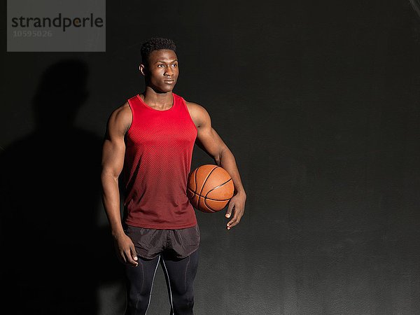 Portrait eines Basketballspielers mit Ball  schwarzer Hintergrund