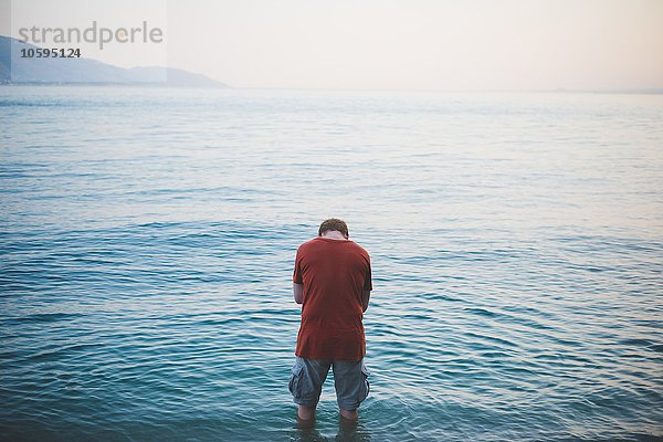 Mann mit Kopf unten stehend im Gardasee  Italien