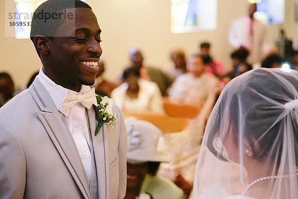 Bräutigam in der kirchlichen Trauung lächelt die Braut an.