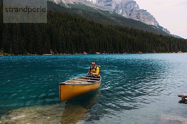 Mid adult man paddeln Kanu auf Moraine Lake  Blick auf die Kamera  Banff National Park  Alberta Kanada