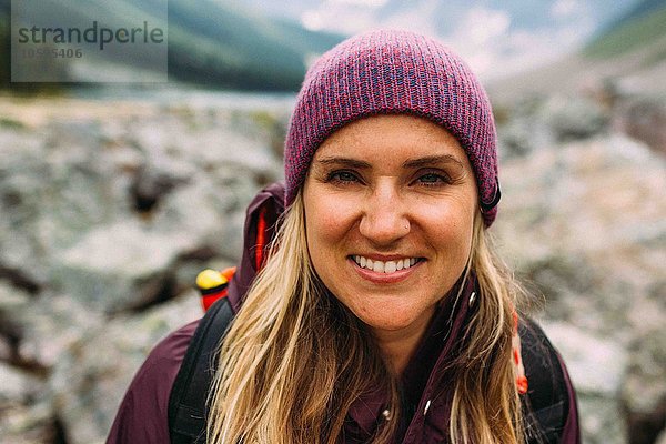 Porträt einer erwachsenen Frau mit Strickmütze  die lächelnd auf die Kamera blickt  Moraine Lake  Banff National Park  Alberta Canada