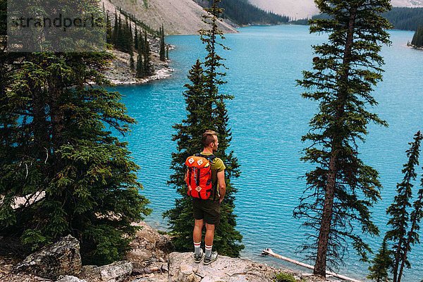 Rückansicht eines erwachsenen Mannes am Felsrand mit Blick auf den Moraine Lake  Banff National Park  Alberta Canada