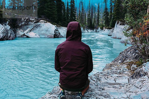 Rückansicht eines erwachsenen Mannes in wasserdichtem Kapuzenmantel am Ufer  Moränensee  Banff National Park  Alberta Canada