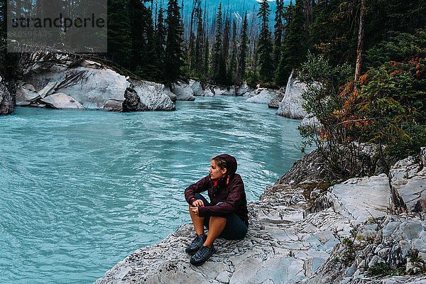 Hochwinkelansicht einer erwachsenen Frau am Wasser sitzend  Moraine Lake  Banff National Park  Alberta Canada